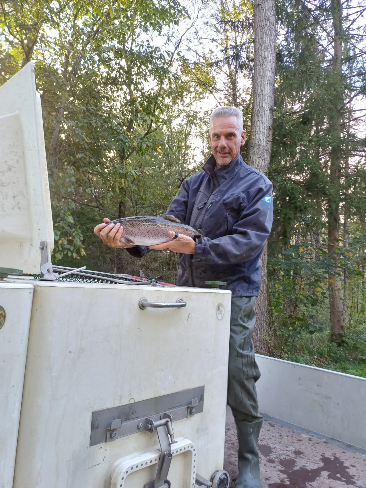 Vereinshelfer mit einer Forelle beim Herbstbesatz